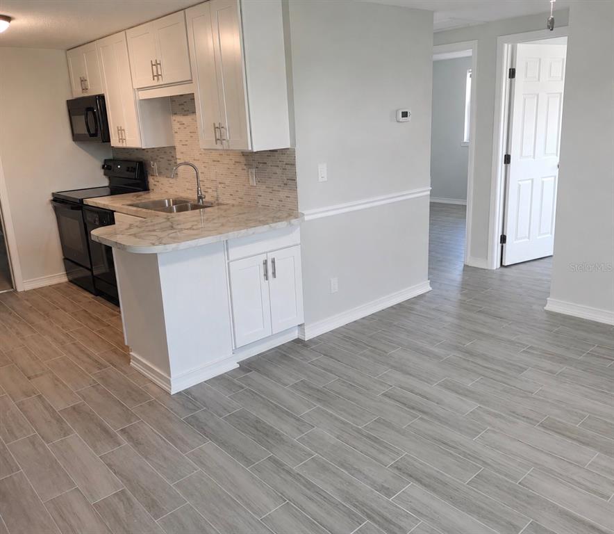 A single-story house with a brick and siding exterior sits on a large grassy lawn — 703 2ND AVENUE NW UNIT B, RUSKIN, FL
