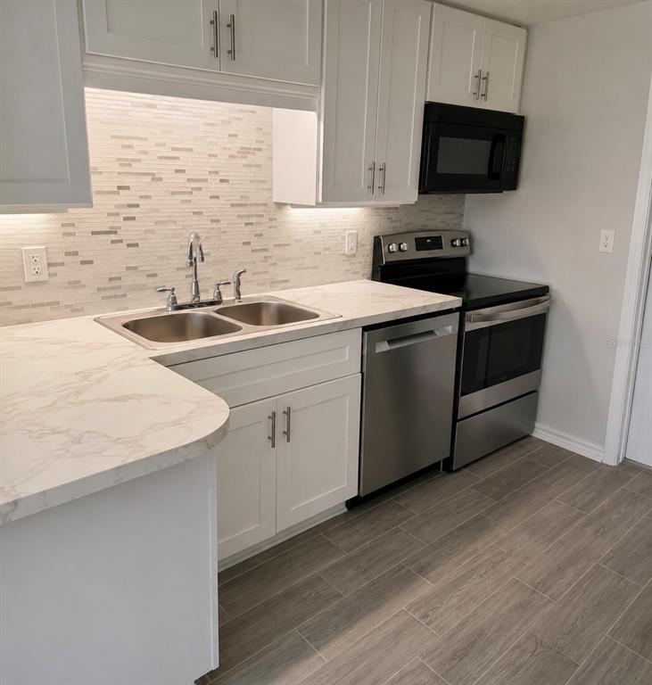 A single-story brick house with a large lawn, palm trees, and a dirt driveway — 703 2ND AVENUE NW UNIT B, RUSKIN, FL