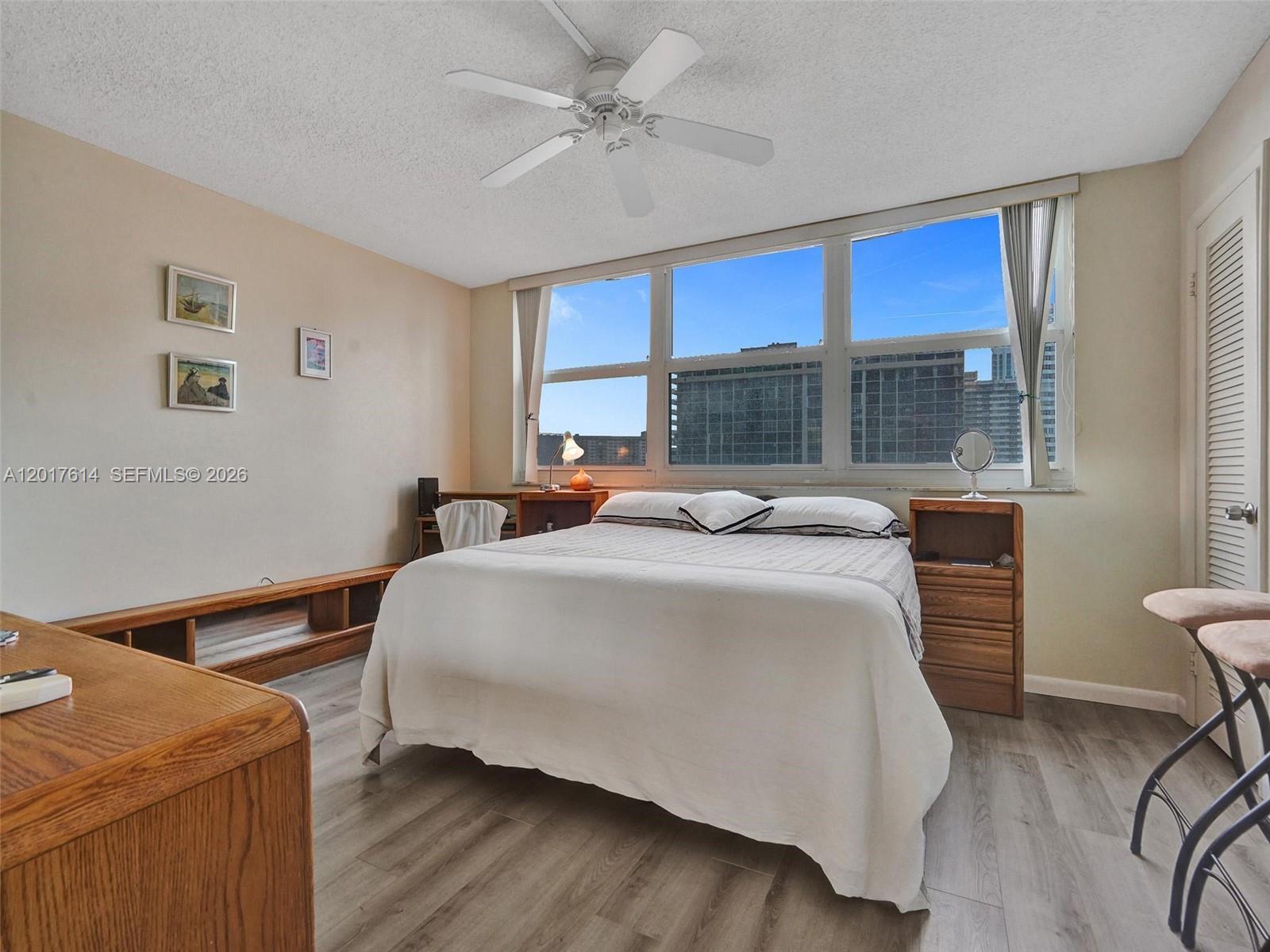 A bedroom features a bed, wood furniture, light flooring, and a large window with city views — 3113 S Ocean Dr # 603, Hallandale Beach FL 33009, HALLANDALE BEACH, FL