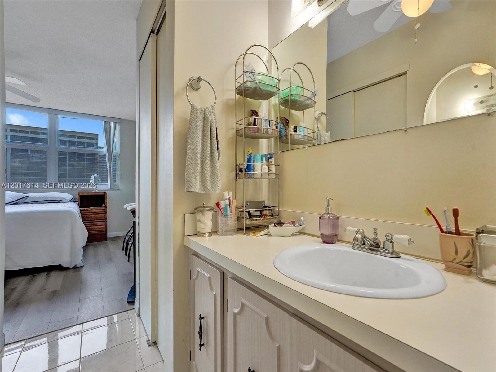 A bathroom vanity with a white sink and metal shelving sits beside a bedroom doorway — 3113 S Ocean Dr # 603, Hallandale Beach FL 33009, HALLANDALE BEACH, FL