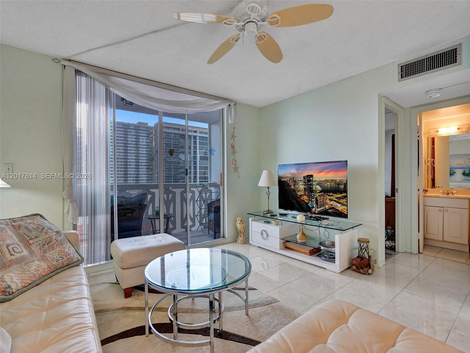 A living room features a glass coffee table, white leather furniture, and a balcony view — 3113 S Ocean Dr # 603, Hallandale Beach FL 33009, HALLANDALE BEACH, FL