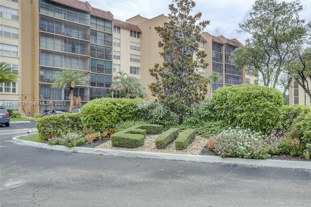 A multi-story apartment building stands behind a landscaped garden with a shaped hedge — 3771 Environ Blvd # 253, Lauderhill FL 33319, LAUDERHILL, FL