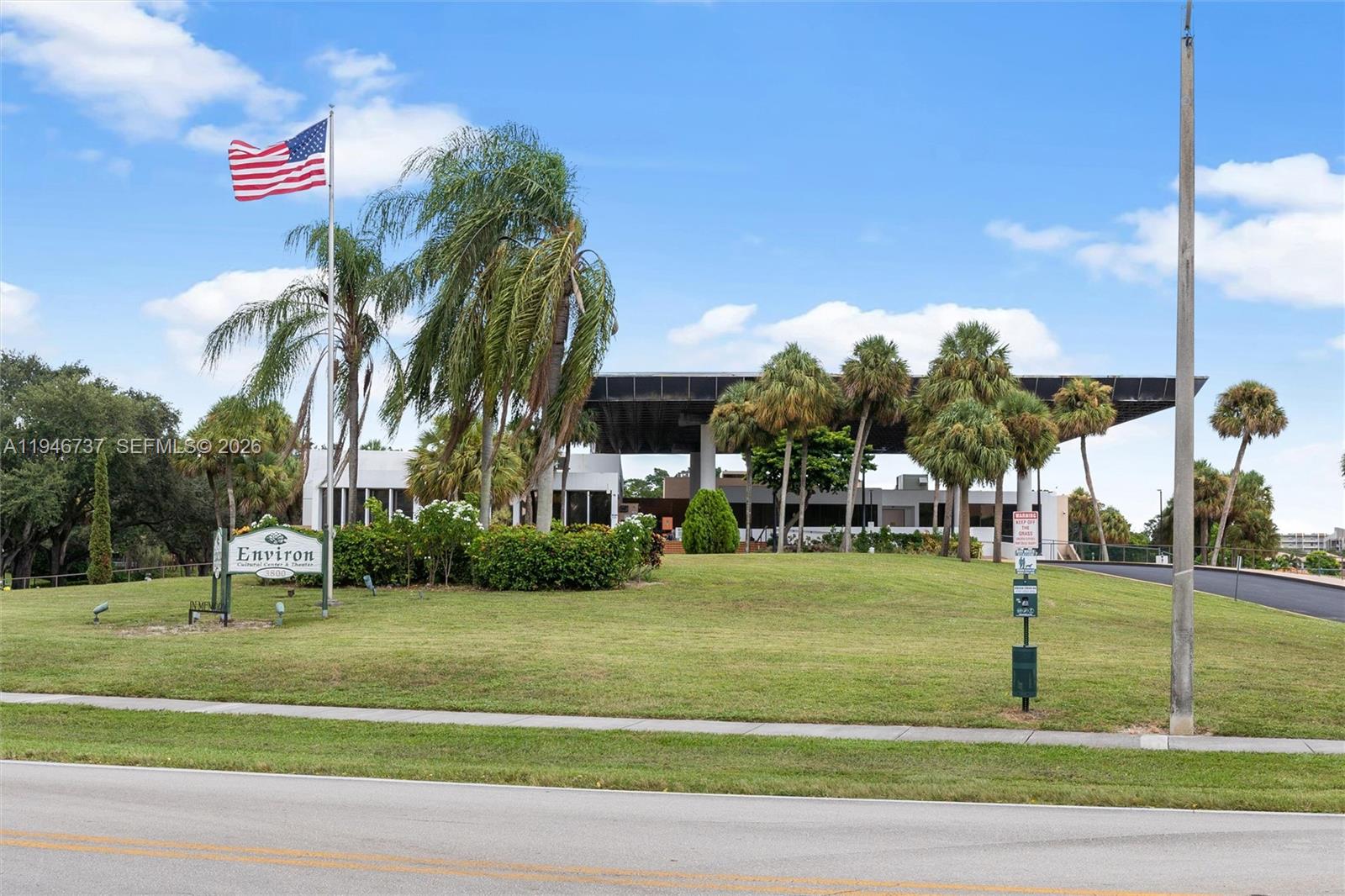 A grassy lawn leads to a modern building with a large overhang and palm trees — 3771 Environ Blvd # 253, Lauderhill FL 33319, LAUDERHILL, FL
