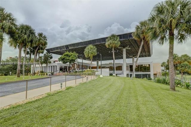 A modern building with a large, flat, overhanging roof stands above a landscaped lawn — 3771 Environ Blvd # 253, Lauderhill FL 33319, LAUDERHILL, FL