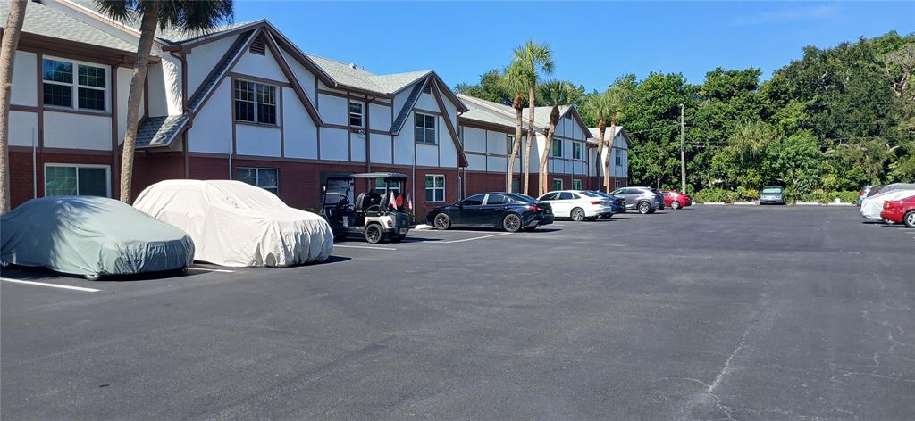 A parking lot sits in front of a multi-story building with a Tudor-style exterior — 650 PINELLAS POINT DRIVE S UNIT 110, ST PETERSBURG, FL