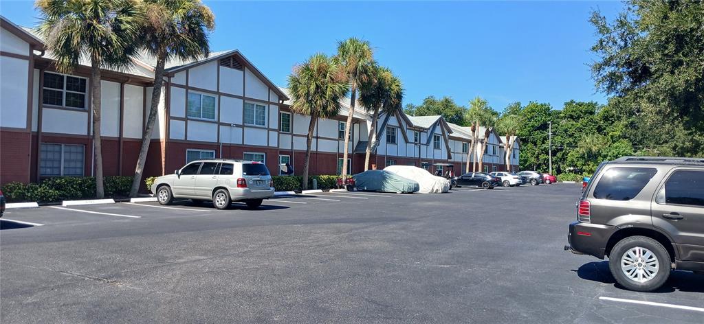A parking lot sits in front of a multi-story apartment building with palm trees — 650 PINELLAS POINT DRIVE S UNIT 110, ST PETERSBURG, FL