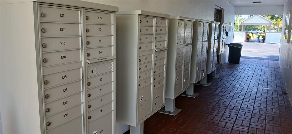 A row of metal mailboxes lines a covered outdoor walkway with brick flooring — 650 PINELLAS POINT DRIVE S UNIT 110, ST PETERSBURG, FL