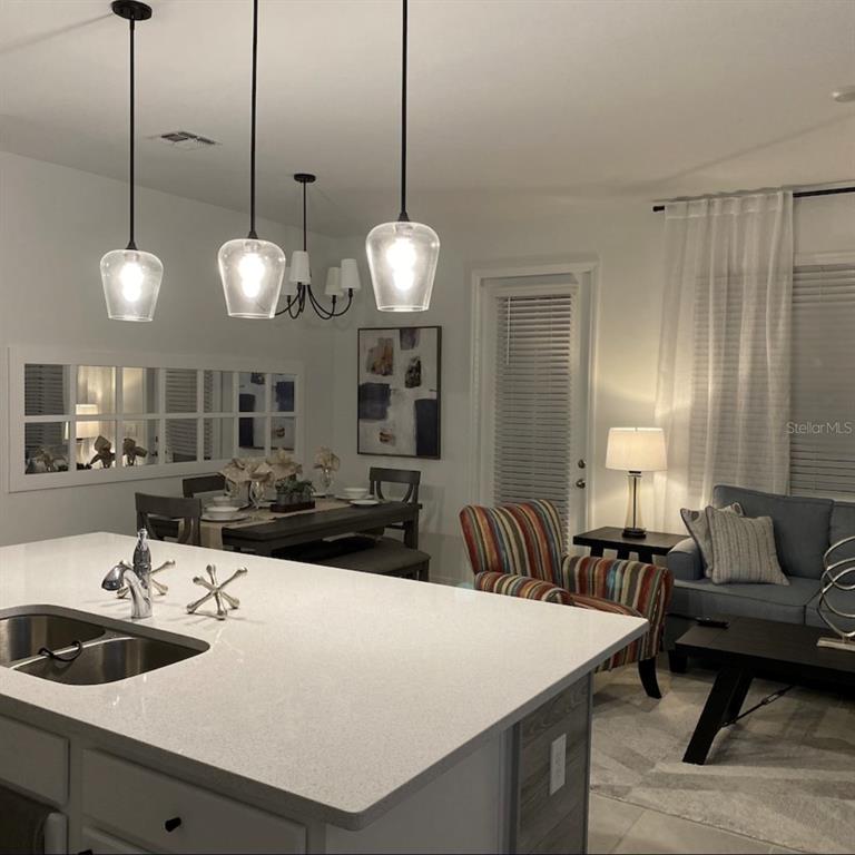 A kitchen island with a white countertop overlooks a dining area and a living room — 1546 DISCOVERY STREET, DAVENPORT, FL