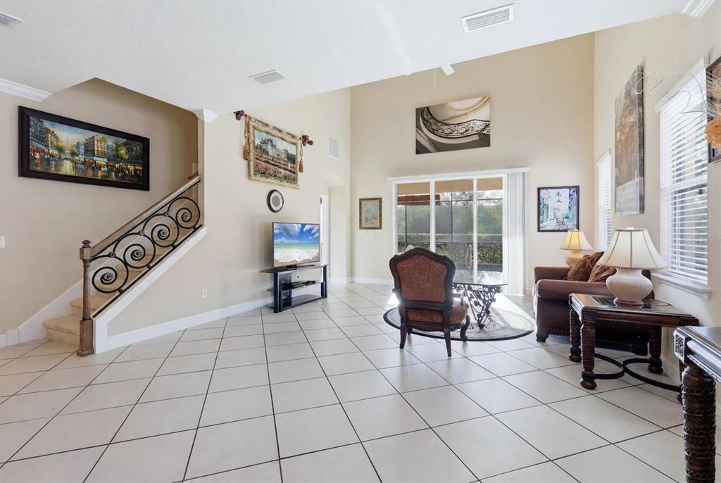 A living room with tile flooring, a staircase with iron railings, and a glass sliding door — 843 MOLLY CIRCLE, SARASOTA, FL
