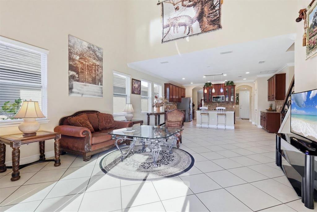 A living room with tile floors, a glass coffee table, and an open kitchen beyond — 843 MOLLY CIRCLE, SARASOTA, FL