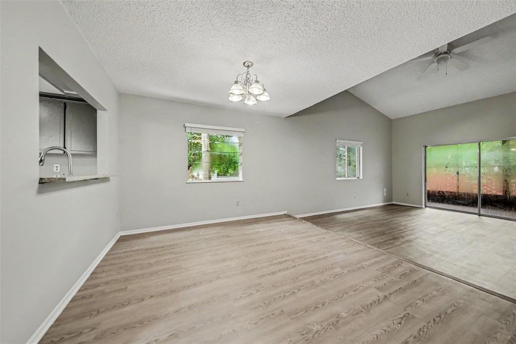 An open-concept living and dining area features light wood-look flooring, gray walls, and a chandelier — 871 BEACH BREEZE DRIVE, ORLANDO, FL