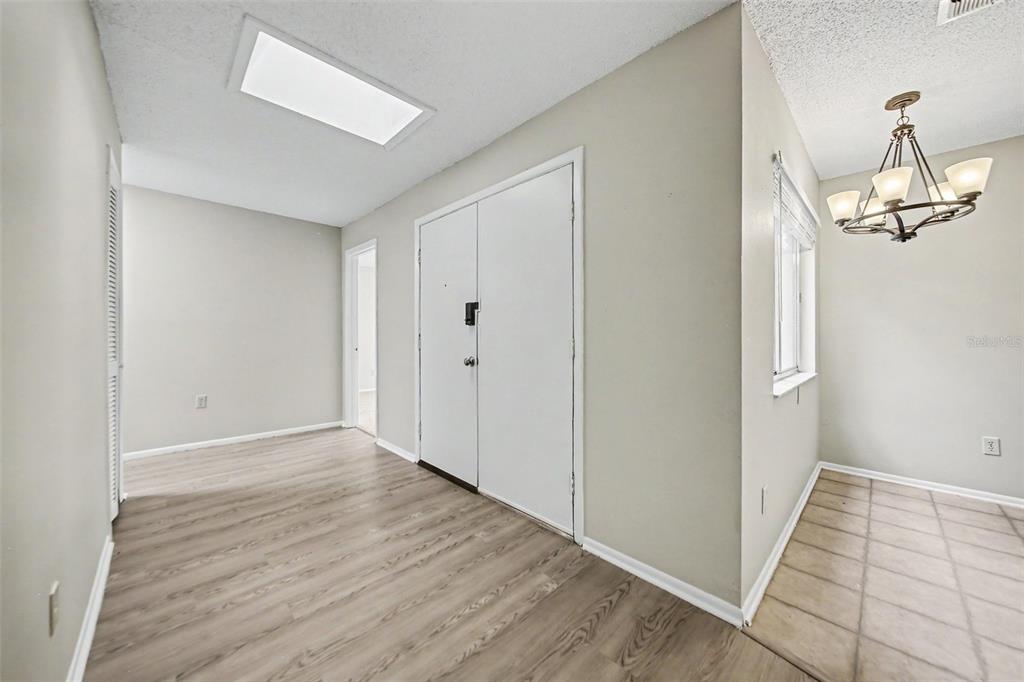 An interior view shows a room with light wood-look flooring, a white door, and a chandelier — 871 BEACH BREEZE DRIVE, ORLANDO, FL