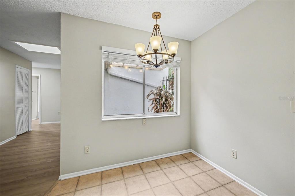 A dining area features a chandelier, a window with blinds, and light-colored tile flooring — 871 BEACH BREEZE DRIVE, ORLANDO, FL