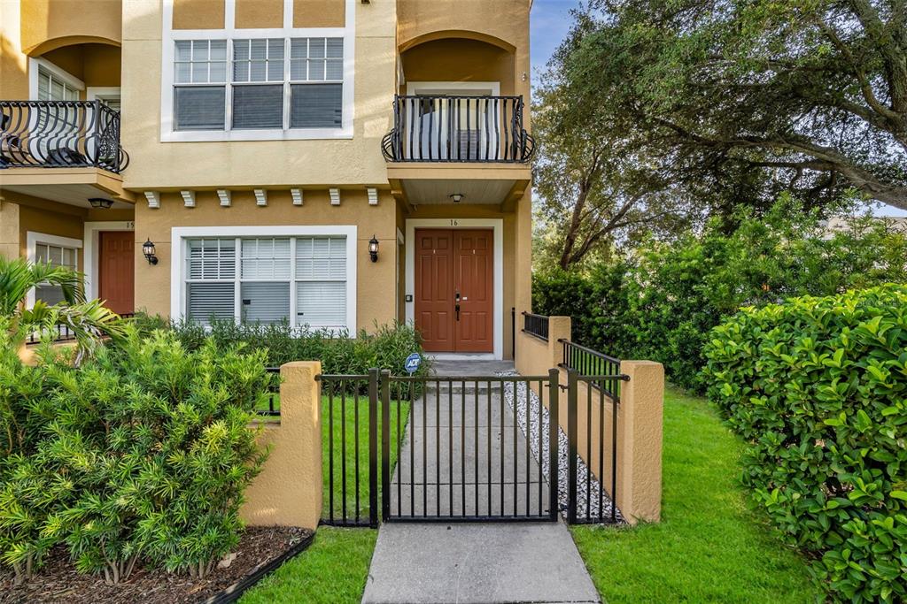 A two-story townhouse exterior features a gated walkway, a brown double door, and balconies — 111 N ALBANY AVENUE UNIT 16, TAMPA, FL