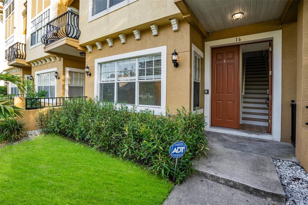 The exterior of a tan multi-story building features a brown front door and landscaping — 111 N ALBANY AVENUE UNIT 16, TAMPA, FL