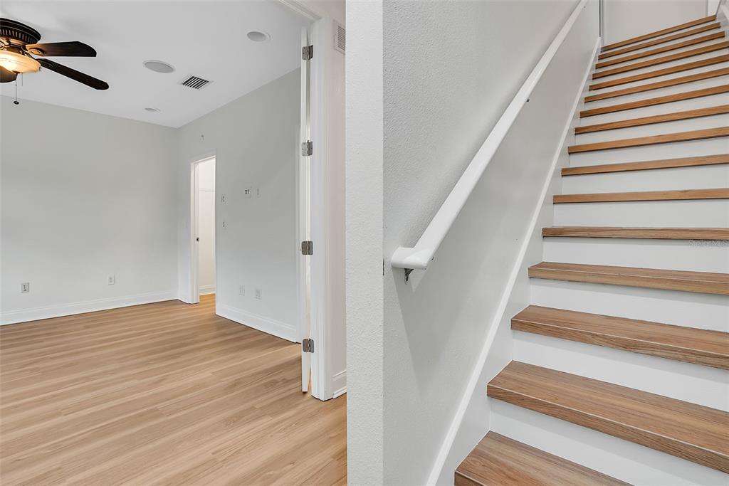 A room with light wood flooring and a ceiling fan leads to a staircase — 111 N ALBANY AVENUE UNIT 16, TAMPA, FL