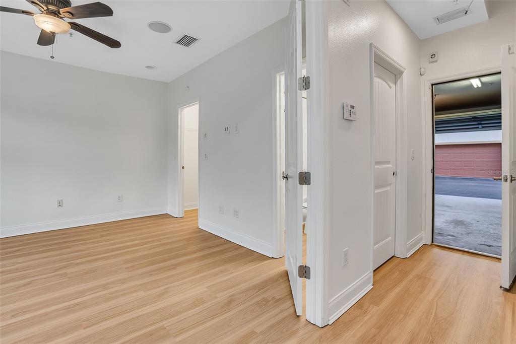 A room with light wood flooring, a ceiling fan, and doorways leading to a closet, bathroom, and garage — 111 N ALBANY AVENUE UNIT 16, TAMPA, FL