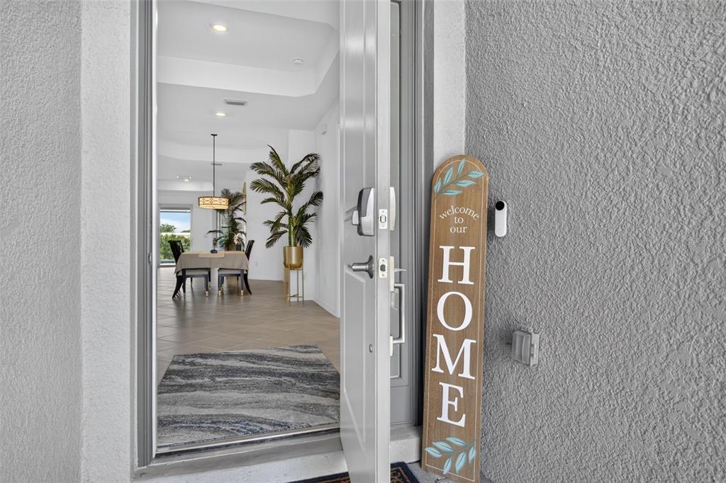 A view through an open front door reveals a dining area with tile flooring — 17260 JADESTONE COURT, VENICE, FL