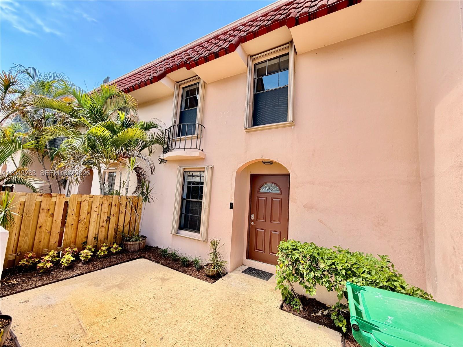 The exterior of a two-story peach-colored townhouse features a brown front door and palm trees — 7361 SW 26th Ct # 84, Davie FL 33314, DAVIE, FL