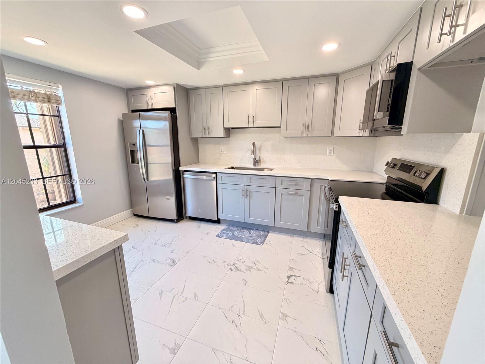 A kitchen features grey cabinets, stainless steel appliances, white quartz countertops, and marble-patterned tile flooring — 7361 SW 26th Ct # 84, Davie FL 33314, DAVIE, FL