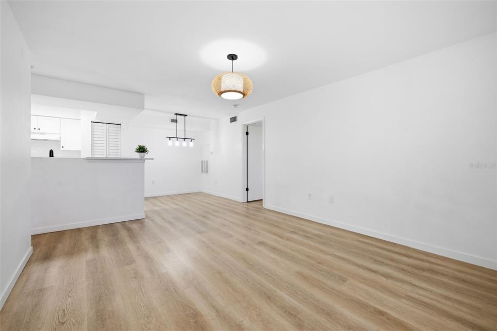 An open-concept living and dining area features light wood-look flooring and white walls — 3038 PARKWAY BOULEVARD UNIT 306, KISSIMMEE, FL