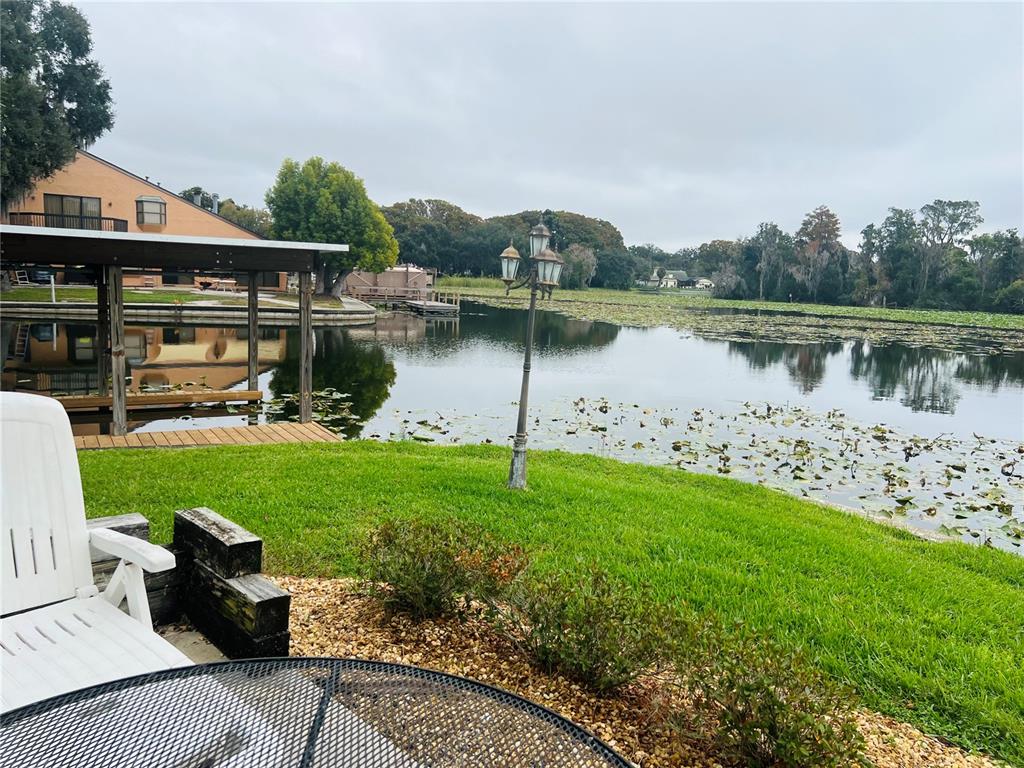 A view of a lake from a grassy backyard with a wooden dock and lamp — 832 PALM HARBOR COURT, LEESBURG, FL