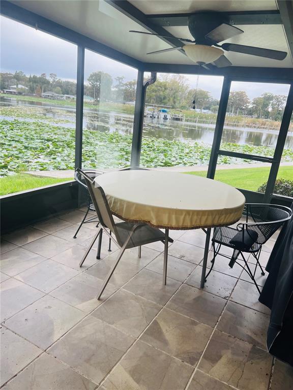 A screened-in patio features tiled flooring, a dining set, and a view of a lake — 832 PALM HARBOR COURT, LEESBURG, FL