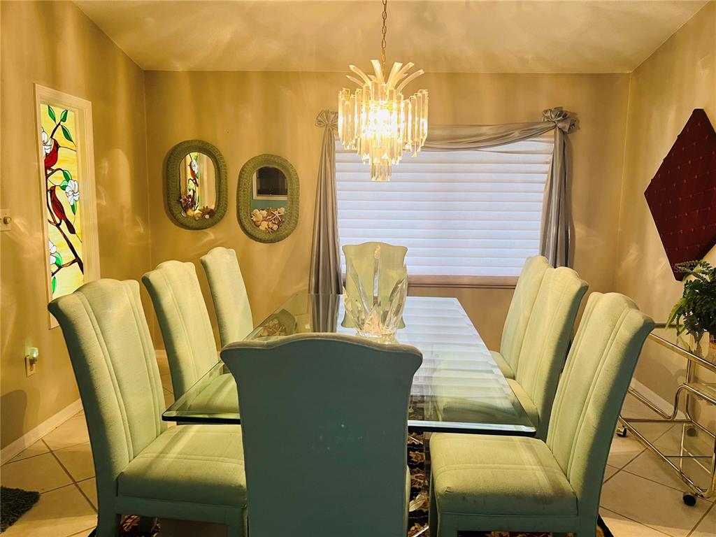 A dining room features a glass-topped table, light green upholstered chairs, and a crystal chandelier — 832 PALM HARBOR COURT, LEESBURG, FL