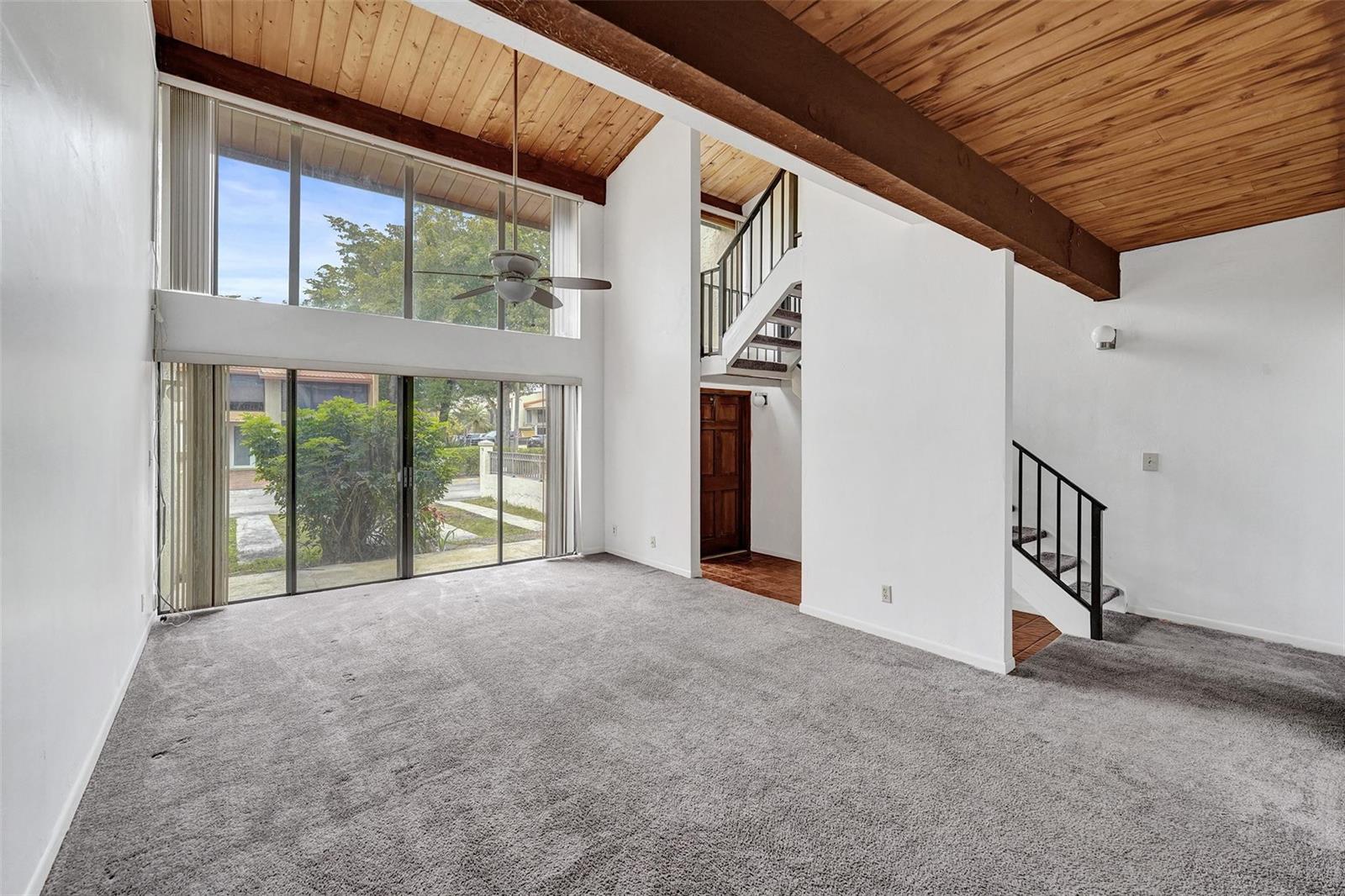 A living room features a vaulted wood-paneled ceiling, floor-to-ceiling windows, and a staircase — 750 E Coco Plum Circle # 2, Plantation FL 33324, PLANTATION, FL