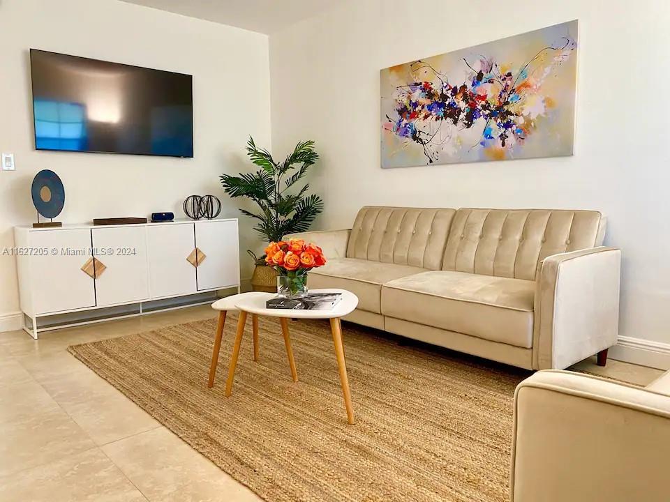 A living room features a beige sofa, a white media console, and a jute rug — 100 Sunrise Dr # 24, Key Biscayne FL 33149, KEY BISCAYNE, FL