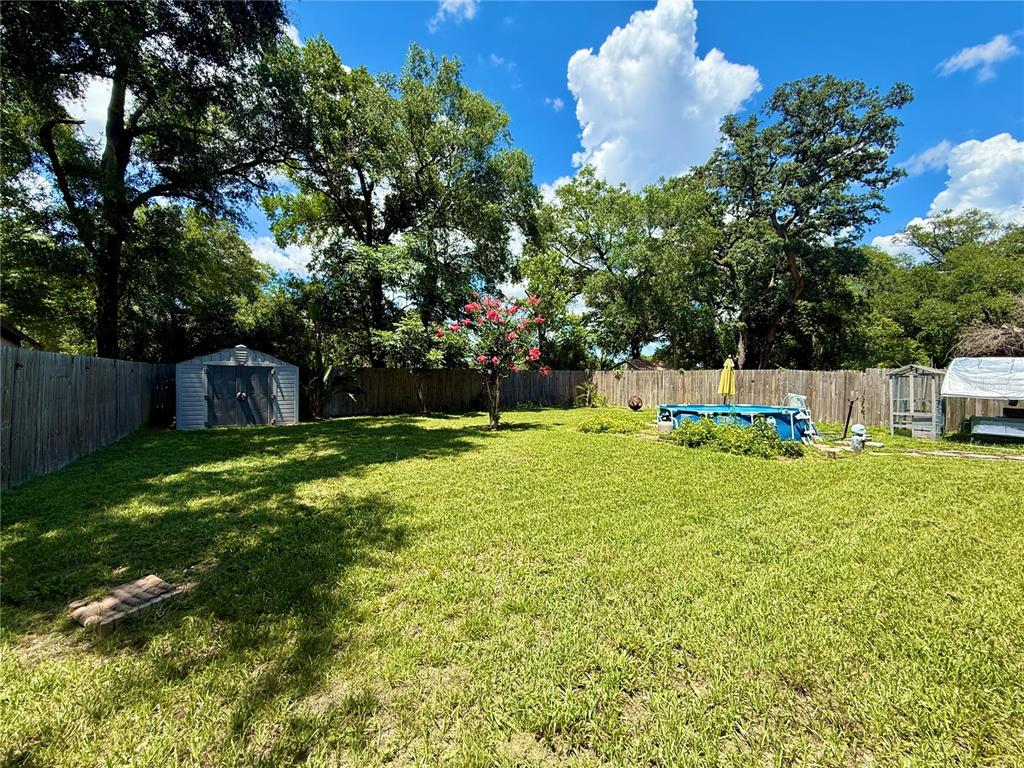 A grassy backyard features a storage shed, a small above-ground pool, and mature trees — 5937 UONA AVENUE, ORLANDO, FL