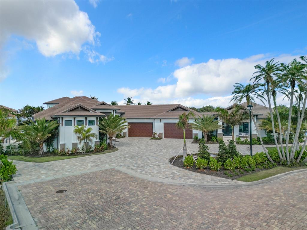 A large house with a paver driveway, three garage doors, and palm trees under blue skies — 14201 BAY DRIVE, FORT MYERS, FL