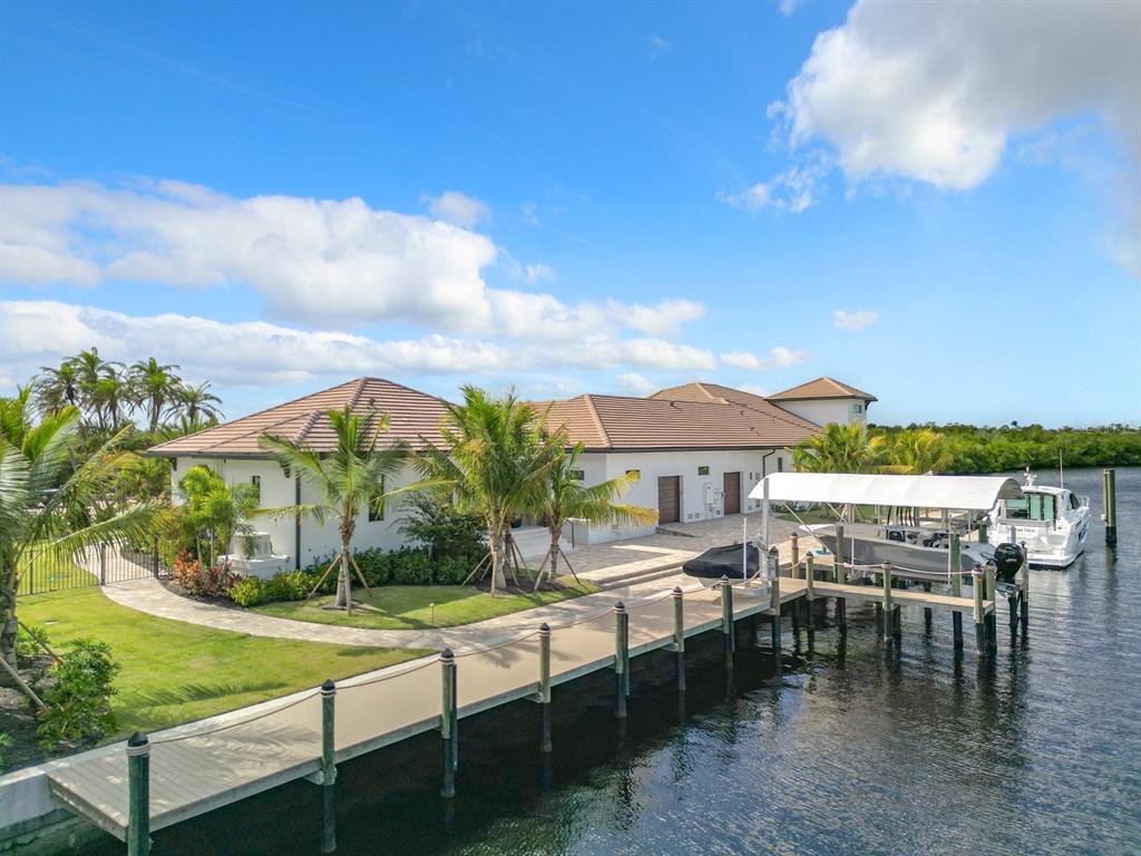 An aerial view of a waterfront house with a dock, boat lift, and palm trees — 14201 BAY DRIVE, FORT MYERS, FL