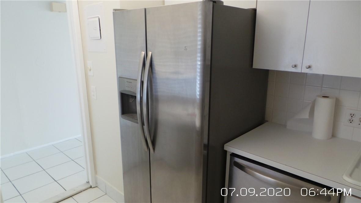 A stainless steel side-by-side refrigerator stands in a kitchen with white cabinets and counters — 2651 S Course Drive # 403, Pompano Beach FL 33069, POMPANO BEACH, FL