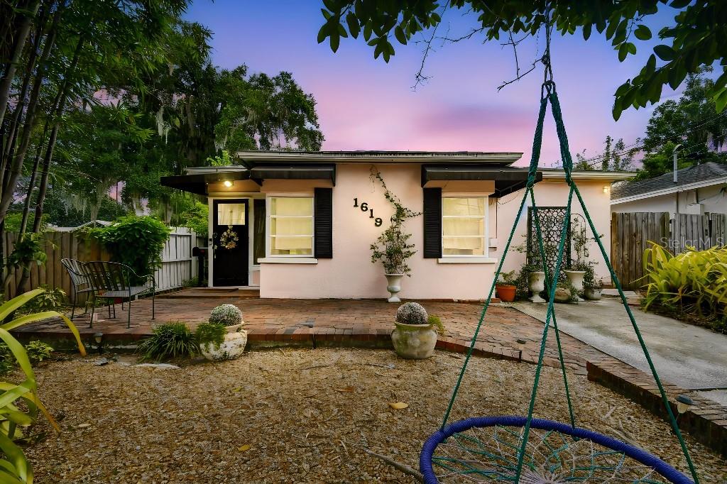 A pink single-story house features a brick patio, black shutters, and a front yard swing — 1619 NEW YORK AVENUE, ORLANDO, FL