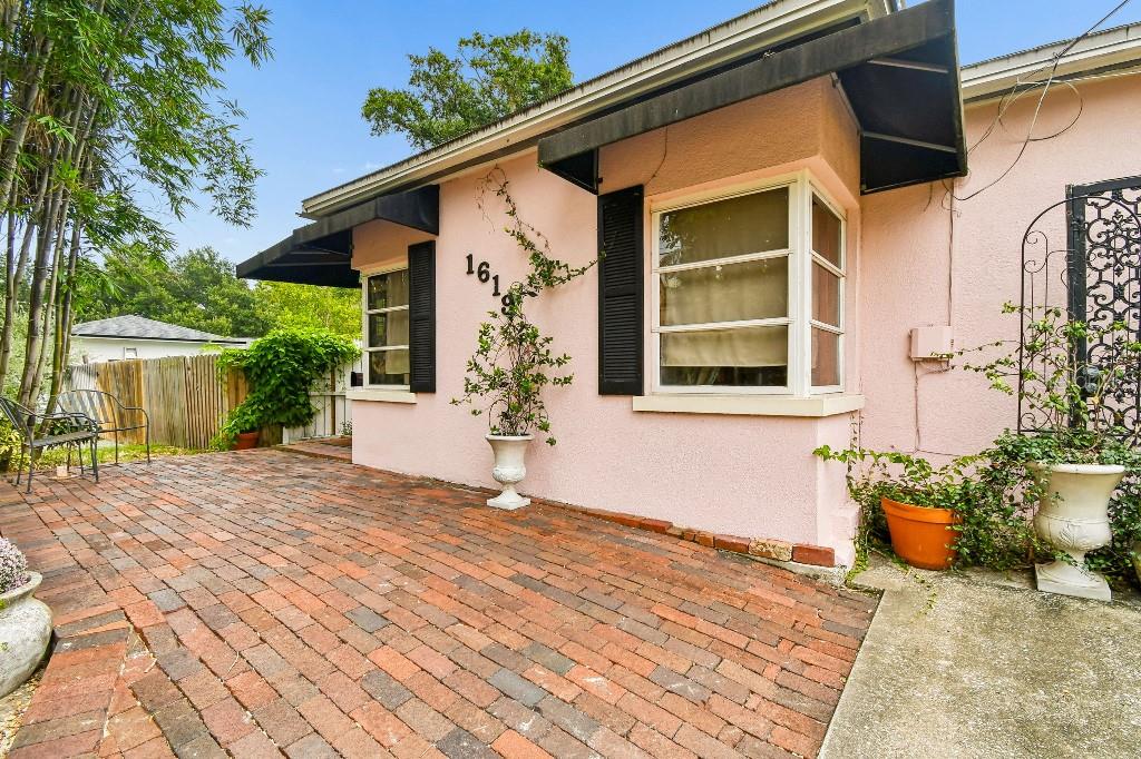 A pink stucco house exterior features a brick patio, bay windows, and black metal awnings — 1619 NEW YORK AVENUE, ORLANDO, FL