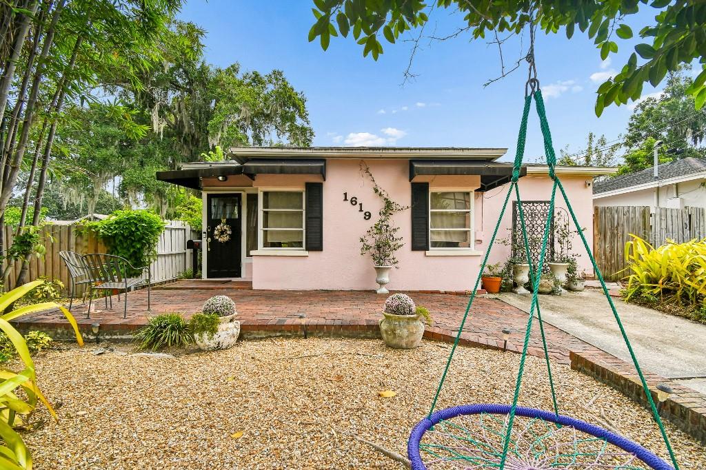 A pink house with a brick patio, black shutters, and a hanging swing in the yard — 1619 NEW YORK AVENUE, ORLANDO, FL