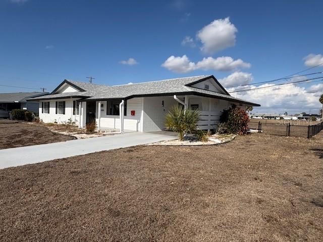 A single-story house with a white exterior, a gray roof, and a concrete driveway — 1021 AUGUSTA DRIVE, SUN CITY CENTER, FL