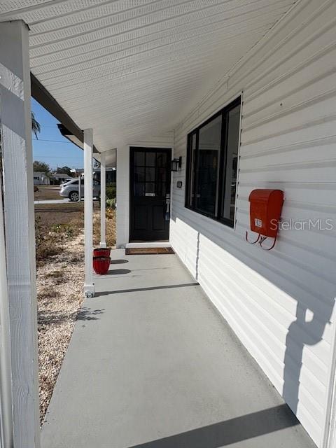 A covered porch with white siding, a dark front door, and a red mailbox — 1021 AUGUSTA DRIVE, SUN CITY CENTER, FL