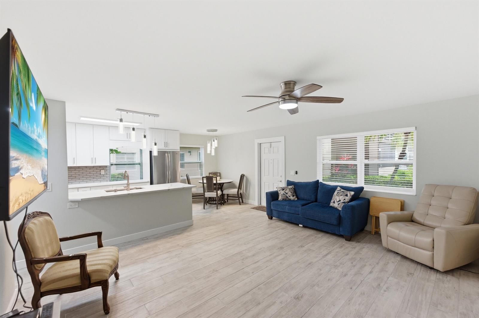 An open-concept living room and kitchen feature light wood-look flooring and a ceiling fan — 634 Normandy N, Delray Beach FL 33484, DELRAY BEACH, FL
