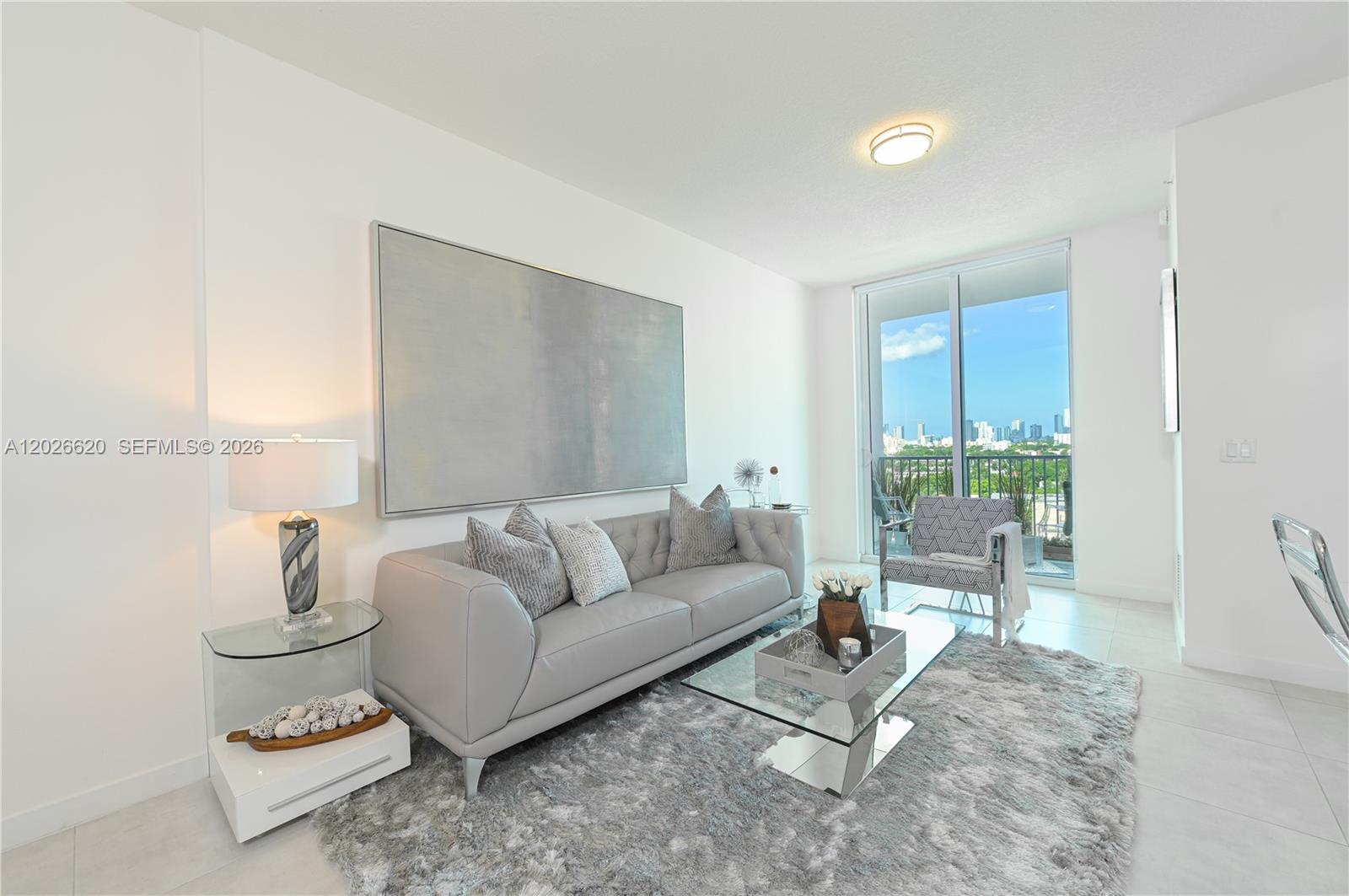 A modern living room features a grey sofa, glass coffee table, and a balcony view — 514 SW 22nd Ave # 405, Miami FL 33135, MIAMI, FL