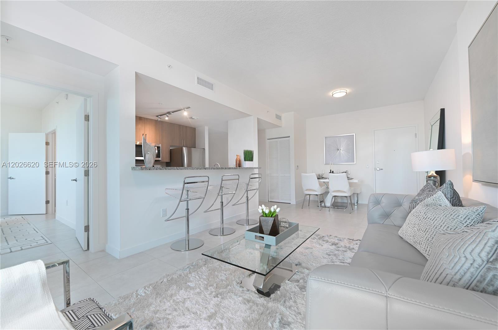 A modern living room features a grey sofa, glass coffee table, and kitchen breakfast bar — 514 SW 22nd Ave # 405, Miami FL 33135, MIAMI, FL