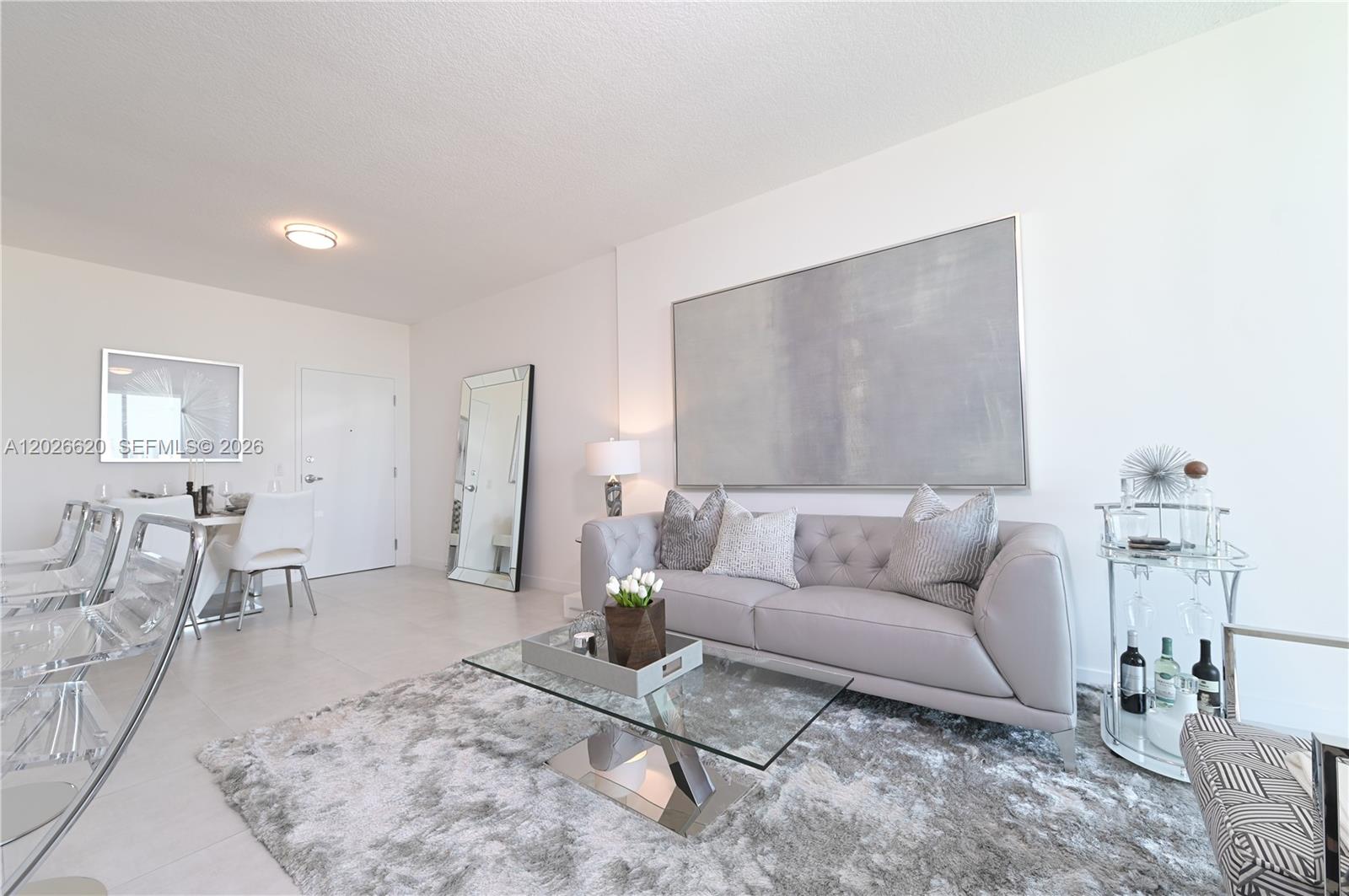 A modern living room features a grey tufted sofa, glass coffee table, and area rug — 514 SW 22nd Ave # 405, Miami FL 33135, MIAMI, FL