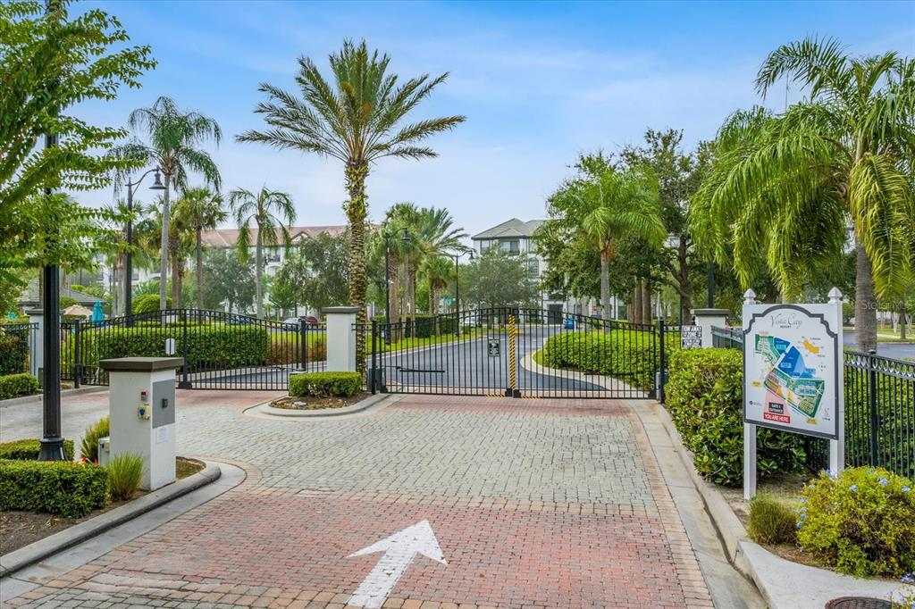A gated entrance with a brick driveway, palm trees, and a community map sign — 4114 BREAKVIEW DRIVE UNIT 20802, ORLANDO, FL