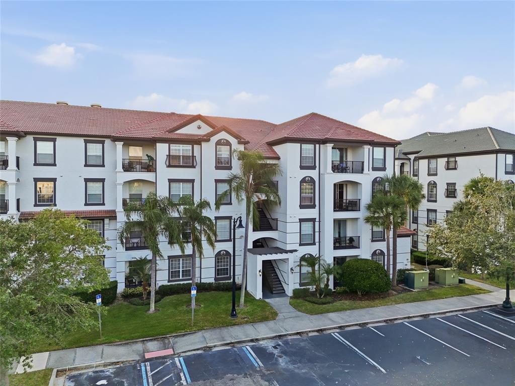 An exterior view of a multi-story apartment building with a tiled roof and parking lot — 4114 BREAKVIEW DRIVE UNIT 20802, ORLANDO, FL