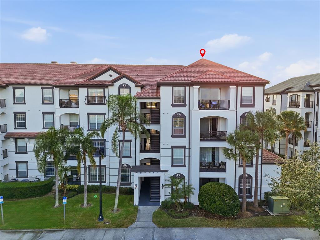 An exterior view of a multi-story apartment building with balconies and a tiled roof — 4114 BREAKVIEW DRIVE UNIT 20802, ORLANDO, FL