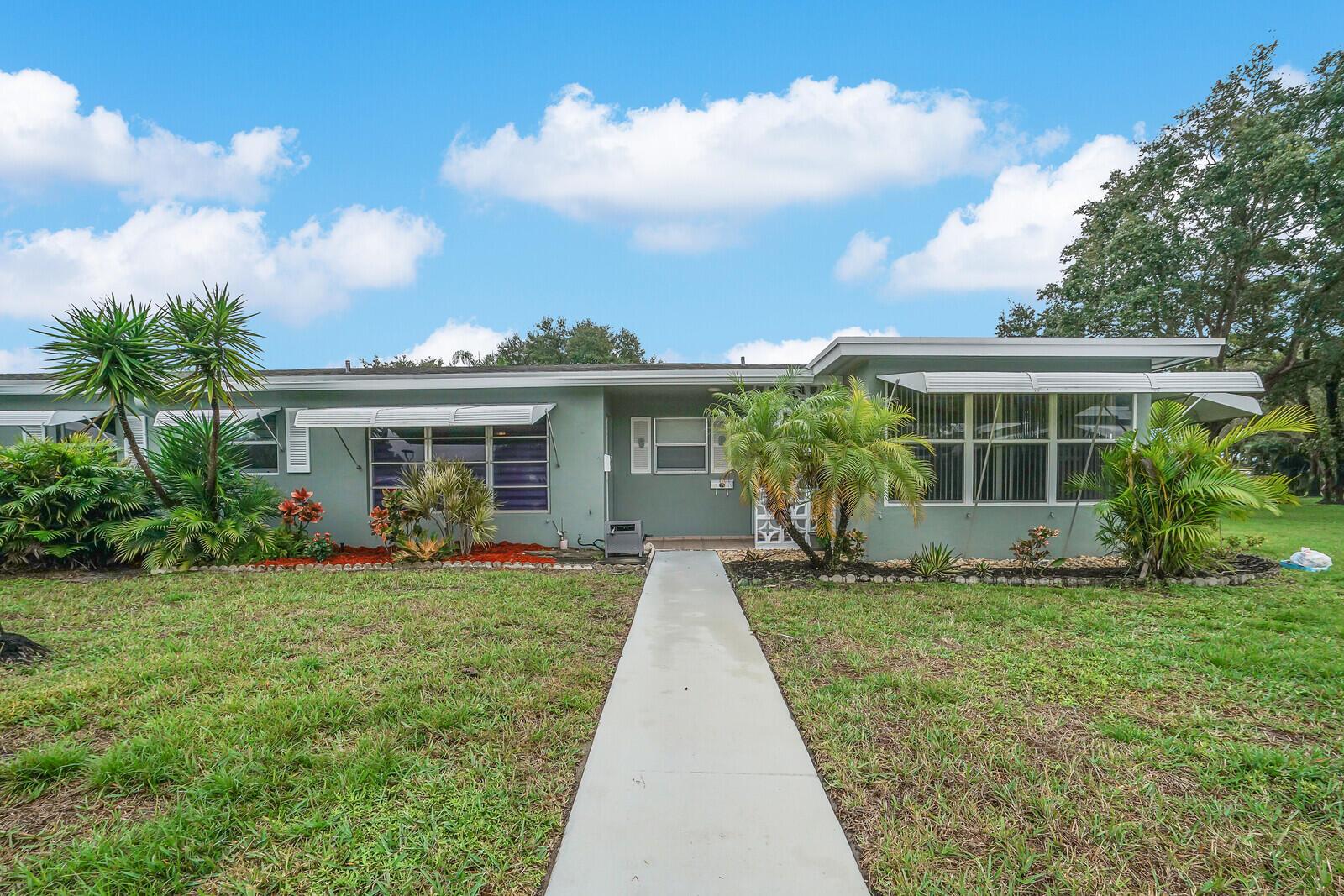 A single-story house with a green exterior, a concrete walkway, and palm trees in front — 902 South Drive # C, Delray Beach FL 33445, DELRAY BEACH, FL