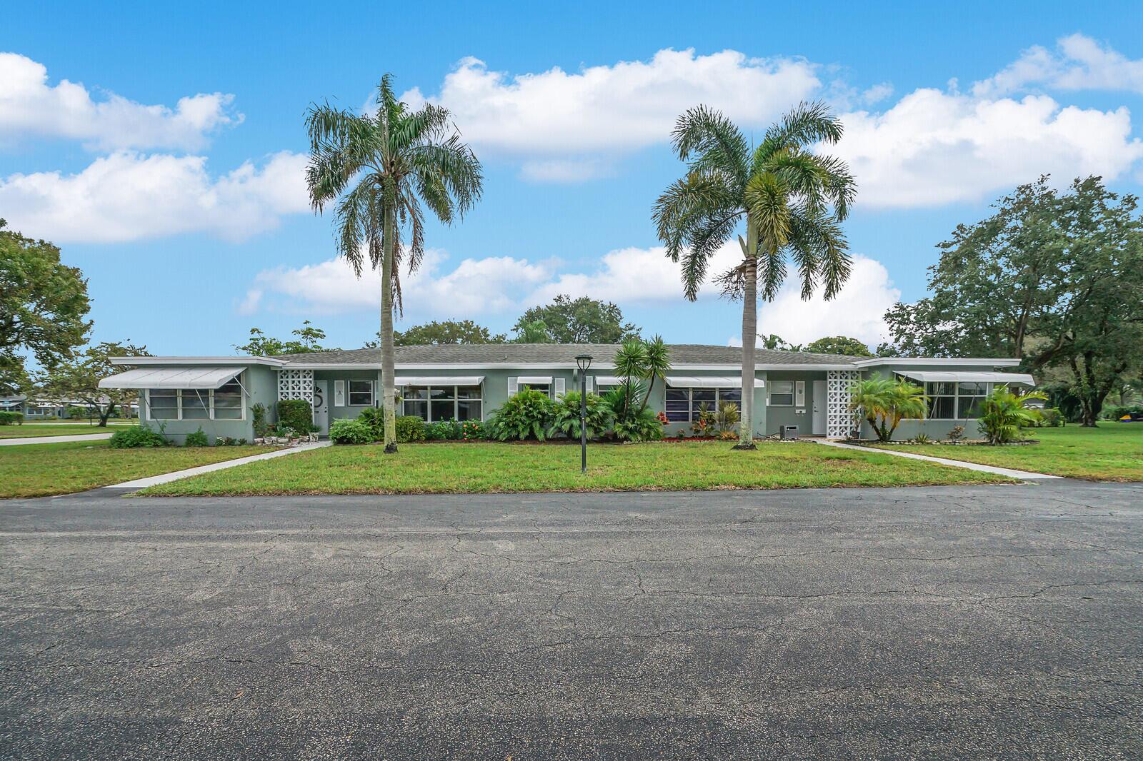 A single-story duplex with a green exterior, two palm trees, and white window awnings — 902 South Drive # C, Delray Beach FL 33445, DELRAY BEACH, FL