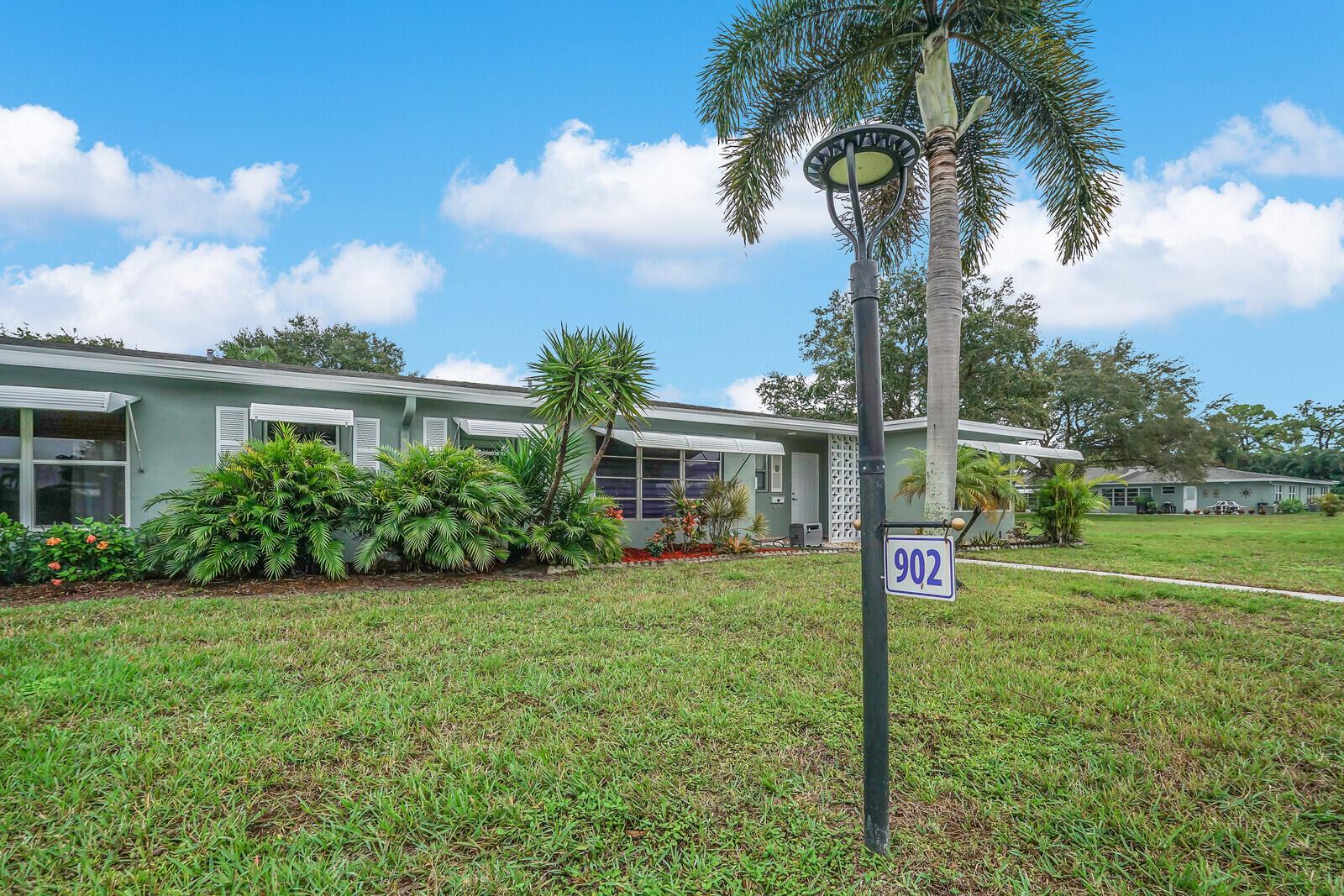 A single-story light green house with a palm tree and a house number sign outside — 902 South Drive # C, Delray Beach FL 33445, DELRAY BEACH, FL