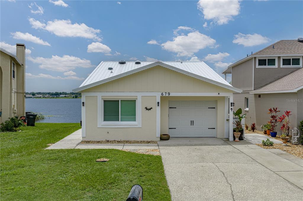 A single-story house with a white metal roof, a garage, and a waterfront backyard — 679 LAKE DEXTER CIRCLE, WINTER HAVEN, FL
